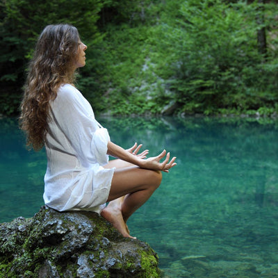 Femme qui medite devant un lac reposée grâce à une séance de sonothérapie
